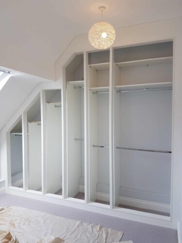 Wardrobe with an unusual ceiling. 7 doors (3 angle and 4 rectangle) Satin White with Cambridge door style.