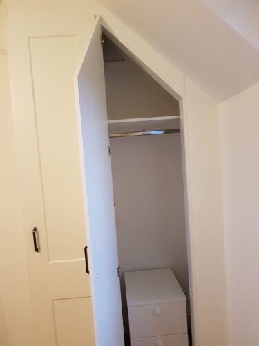 Angled hinged door wardrobe with hanging space and chest of drawers.