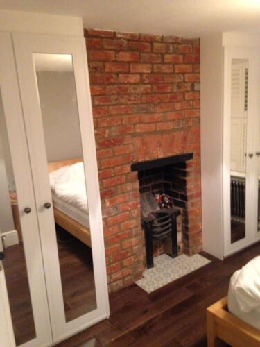 White Hinged Mirror Robes. Double wardrobe on each side of the fireplace.