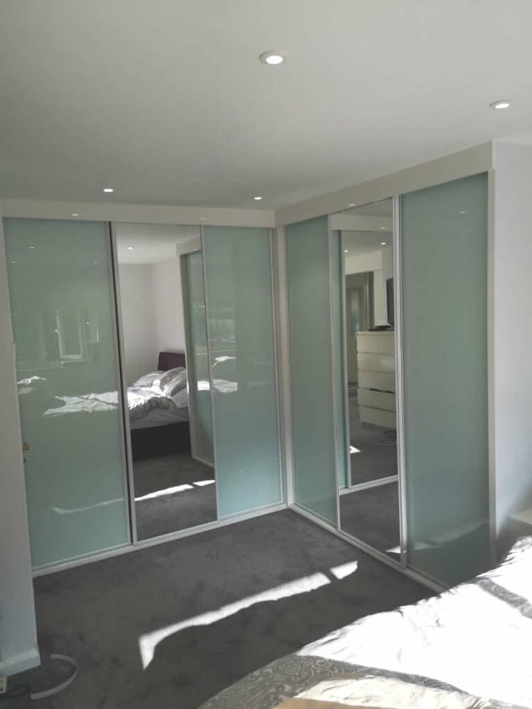 Corner Sliding Wardrobes. White high gloss with soft white and mirror doors in white profile.