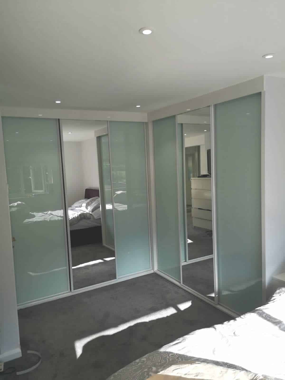 Corner Sliding Wardrobes. White high gloss with soft white and mirror doors in white profile.