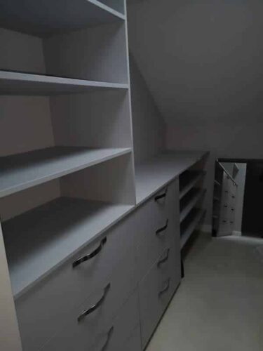 Shelving and drawers in a walk-in wardrobe under the eaves